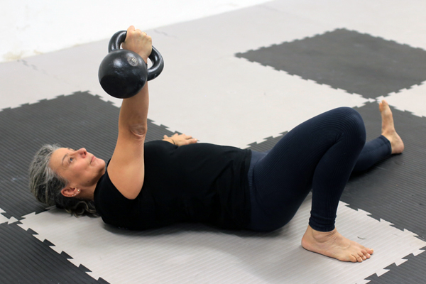Frau auf dem Boden liegend mit Kettlebell